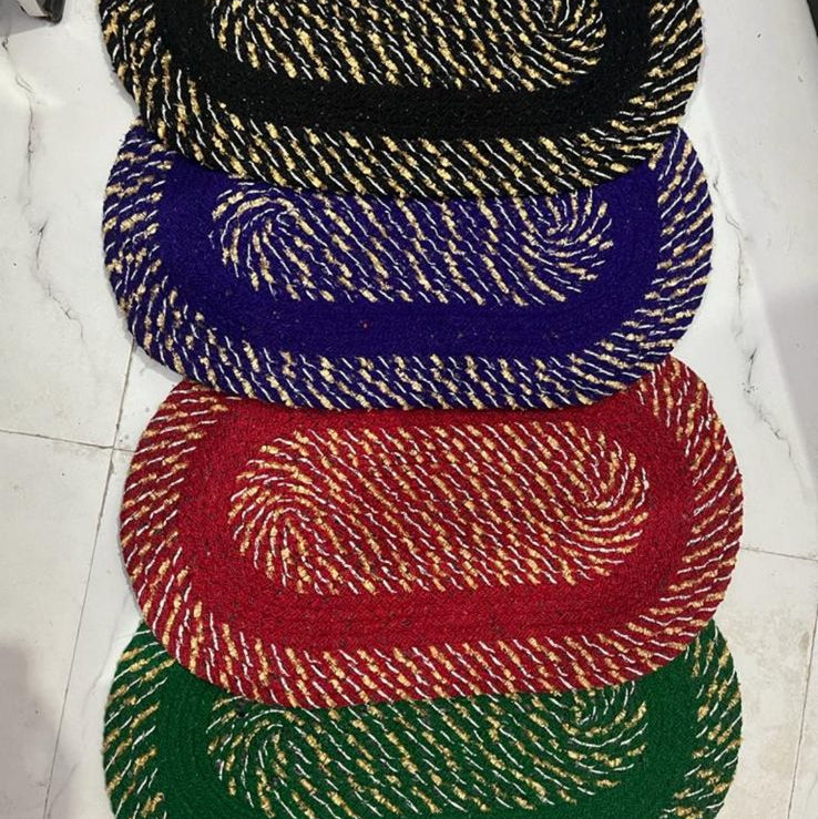 Four woven coasters in black, blue, red, and green on a white surface.