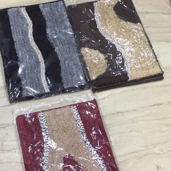 Three patterned rugs in packaging on a wooden floor.