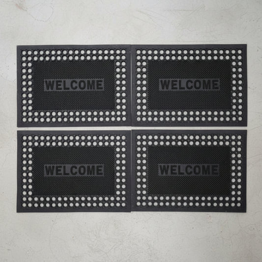 Four black doormats with 'WELCOME' text on a gray background