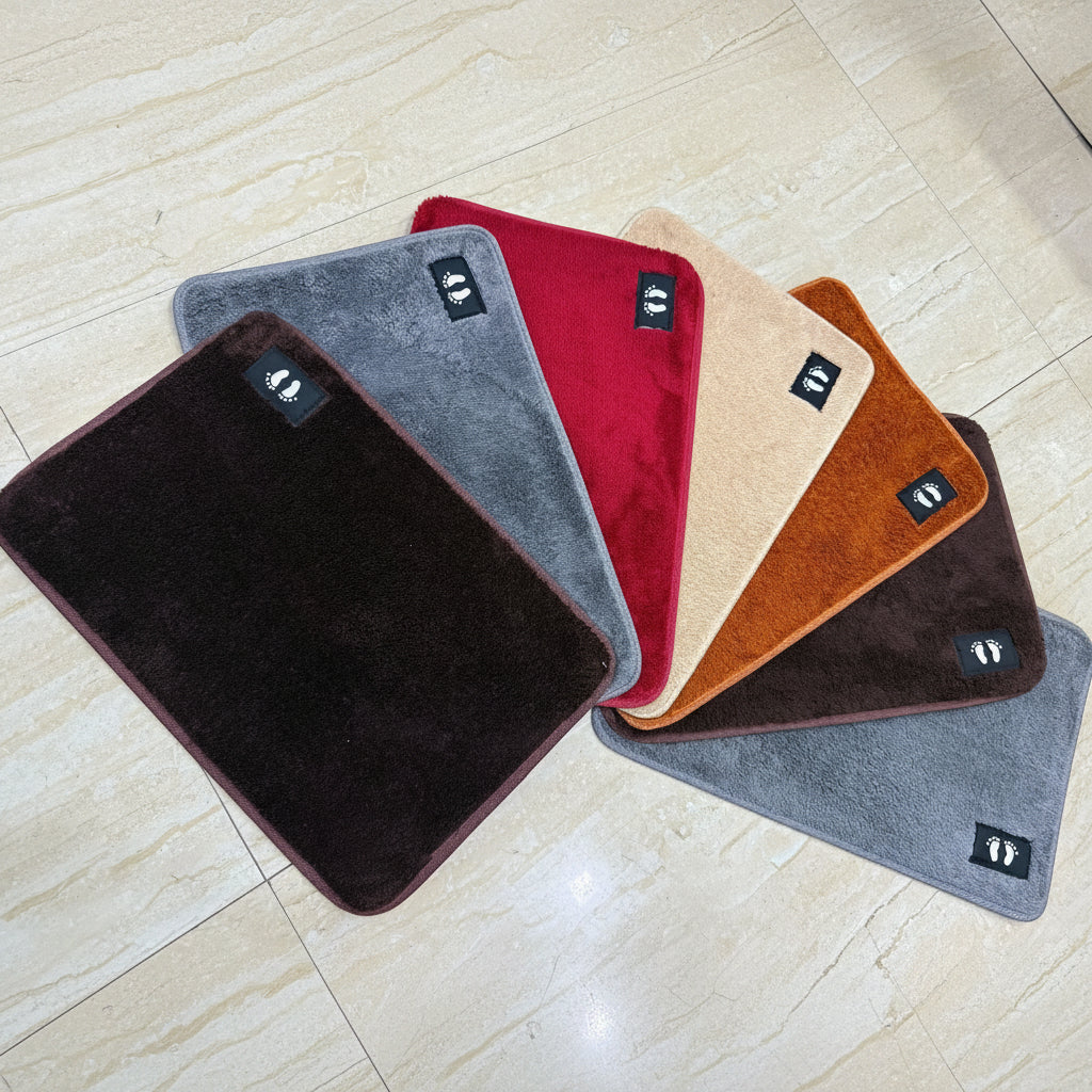 Set of six colorful bath mats on a light wooden floor.