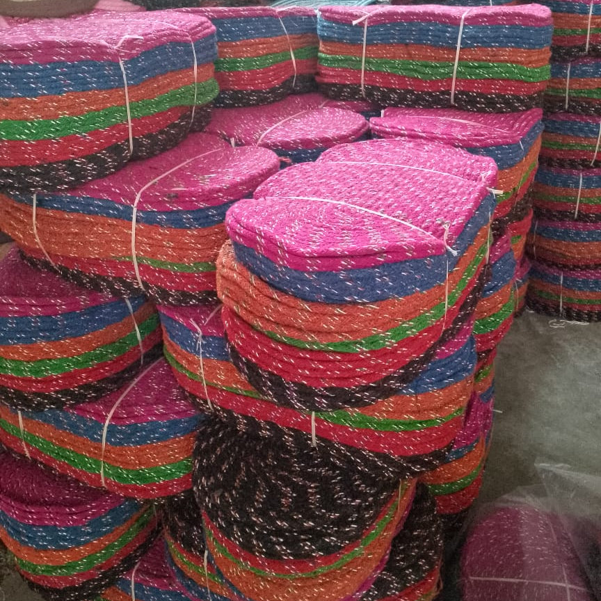 Stacks of colorful woven mats tied together in a warehouse setting.