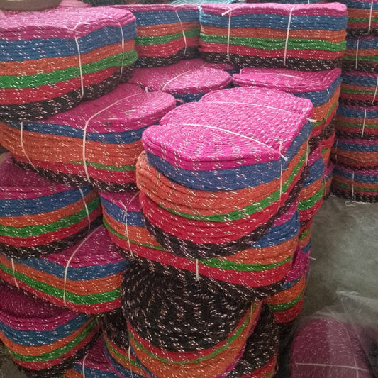 Stacks of colorful woven mats tied together in a warehouse setting.