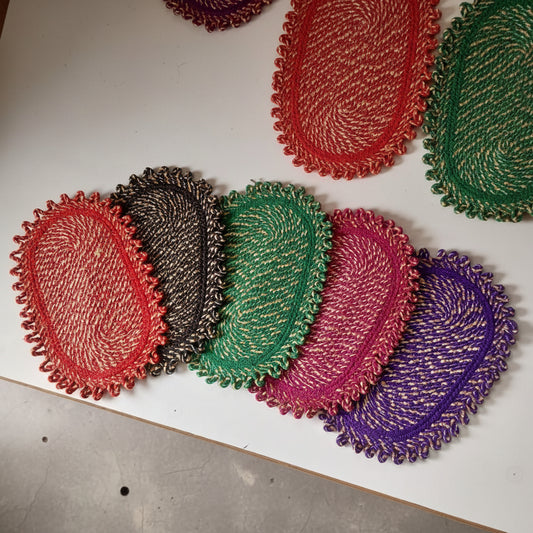 Stack of colorful woven coasters on a white surface