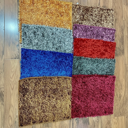 Set of colorful textured rugs arranged in a grid on a wooden floor.