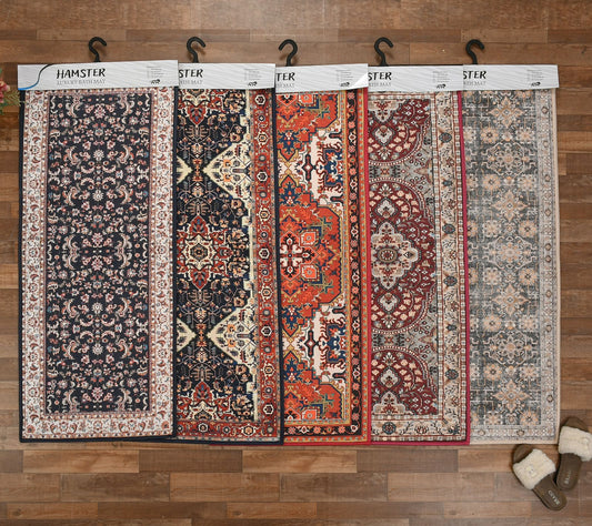 Four patterned rugs displayed on hangers against a wooden wall.