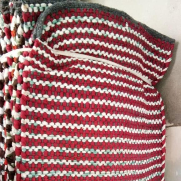 Textured fabric with red, white, and gray pattern on a plain background