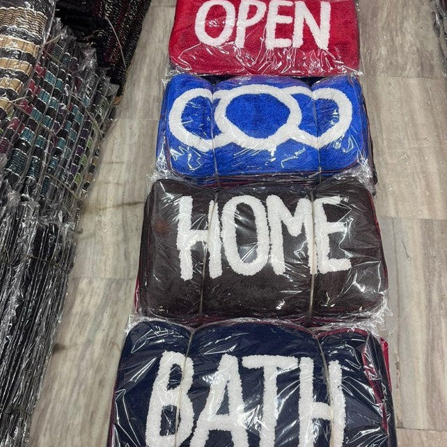 Stack of plastic-wrapped signs with text 'OPEN', 'HOME', and 'BATH' on a wooden floor.