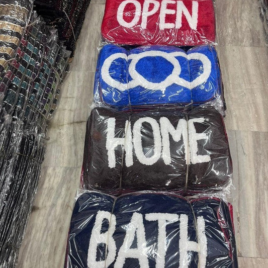 Stack of plastic-wrapped signs with text 'OPEN', 'HOME', and 'BATH' on a wooden floor.
