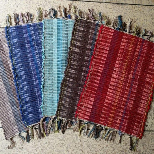 Set of woven placemats in various colors on a wooden surface