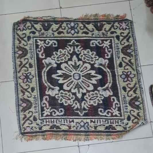 Small decorative rug on a tiled floor with feet wearing sandals around it.