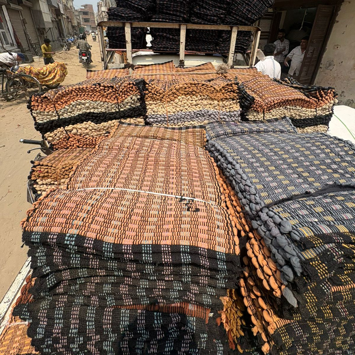 Stacks of woven mats on a truck in an urban street setting