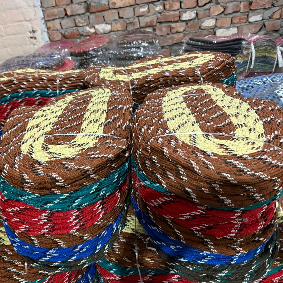 Stack of colorful woven baskets on a table with a brick wall background