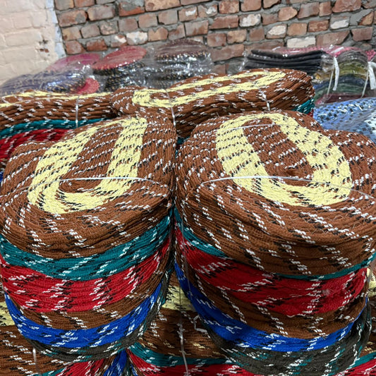 Stack of colorful woven baskets on a table with a brick wall background