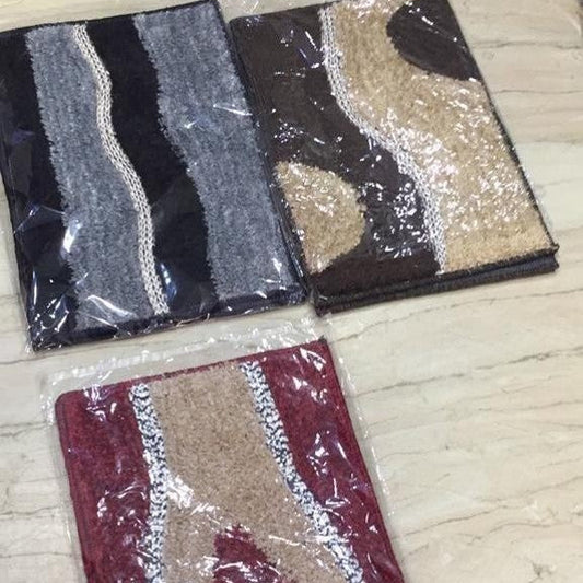 Three patterned rugs in packaging on a wooden floor.
